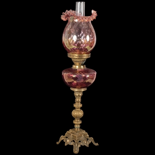 70 - An Antique Duplex glass and brass oil lamp, with a frilled red glass shade and matching font, H68cm