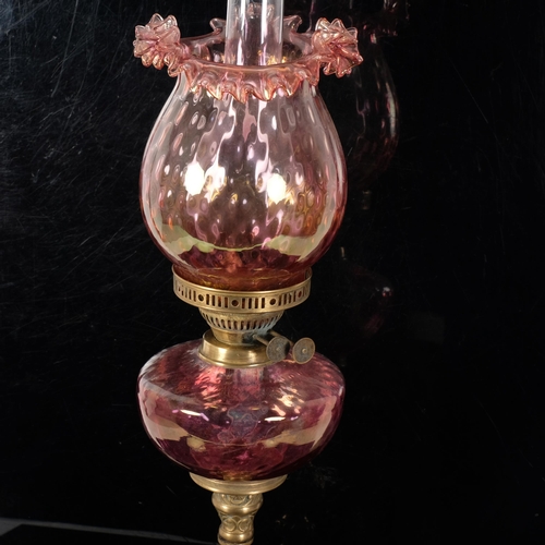 70 - An Antique Duplex glass and brass oil lamp, with a frilled red glass shade and matching font, H68cm