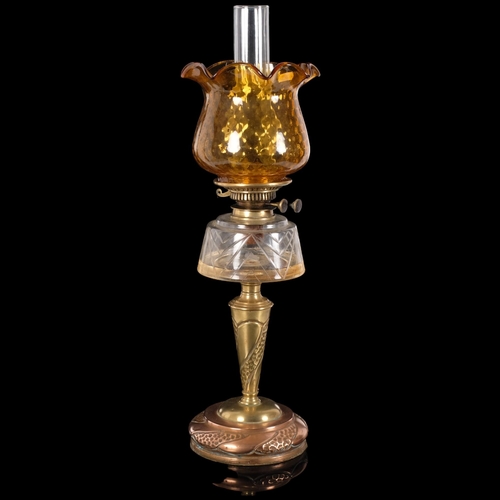 71 - An Art Nouveau copper and brass oil lamp, with an amber frilled edge shade, and clear glass font, H6... 