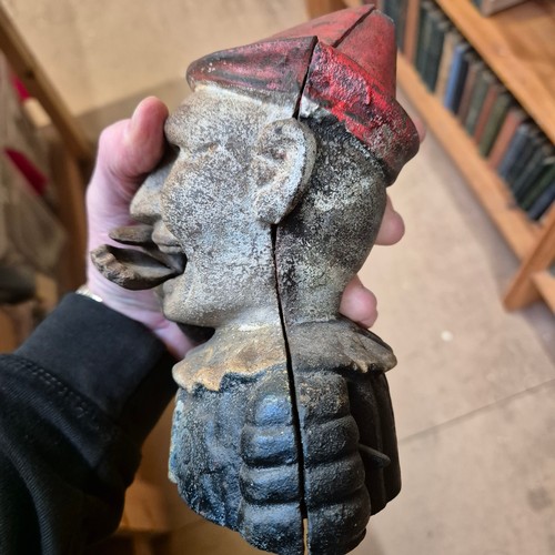 177 - A Vintage cast iron money box in the form of a jester or clown, coin is placed in hand and is fed vi... 