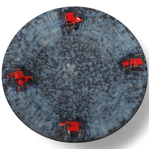 105 - A mid century Brutalist wall hanging plate, with matt blue glaze and red accents, unsigned, diameter... 