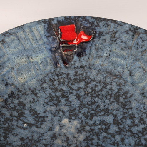 105 - A mid century Brutalist wall hanging plate, with matt blue glaze and red accents, unsigned, diameter... 