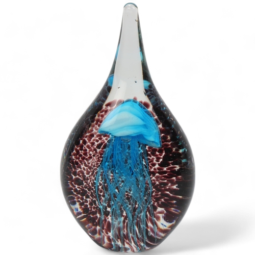 313 - An elongated hand made glass paperweight, with internal blue jellyfish on spotted amethyst backgroun... 