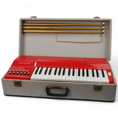 315 - A mid 20th century Italian Companion electric keyboard, red plastic in original fixed carry case and... 