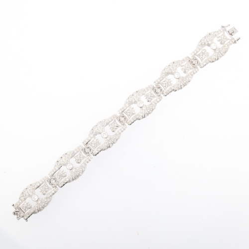 1154 - An Art Deco platinum and diamond panel bracelet, circa 1920s, the 6 panels having openwork fan decor... 