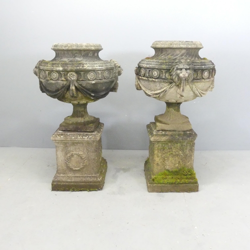 118 - A pair of three-section weathered stone garden urns on plinth stands, with swag and lion mask decora... 