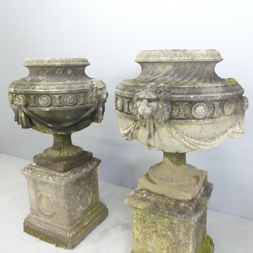 118 - A pair of three-section weathered stone garden urns on plinth stands, with swag and lion mask decora... 