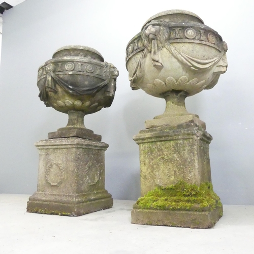 118 - A pair of three-section weathered stone garden urns on plinth stands, with swag and lion mask decora... 