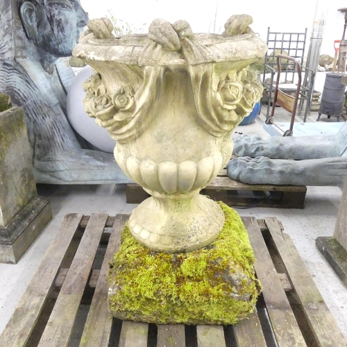 119 - A large and impressive swag nosed urn on weathered stone plinth base. 67x102cm.