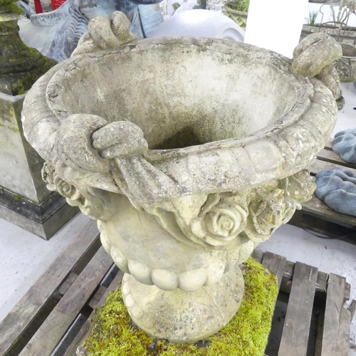 119 - A large and impressive swag nosed urn on weathered stone plinth base. 67x102cm.