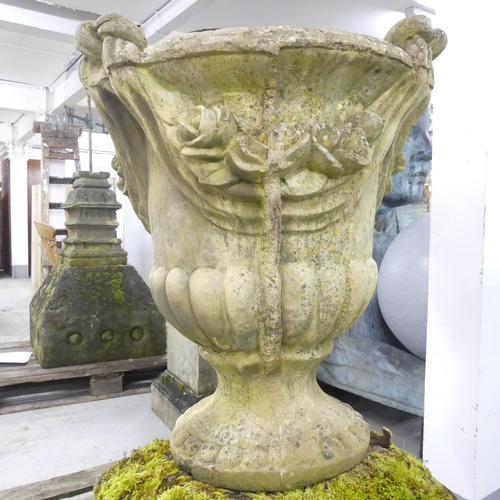 119 - A large and impressive swag nosed urn on weathered stone plinth base. 67x102cm.