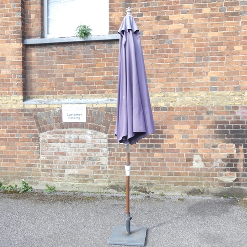 184 - A garden parasol on cast metal base. Approximate height 250cm.