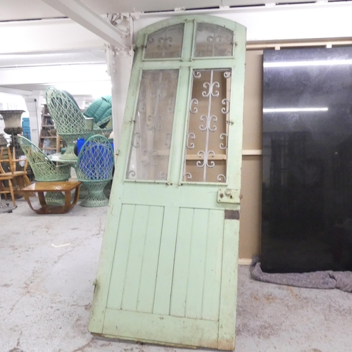 188 - A large panelled arch top door, with opening glass panes and wrought iron decoration. 90x245cm.