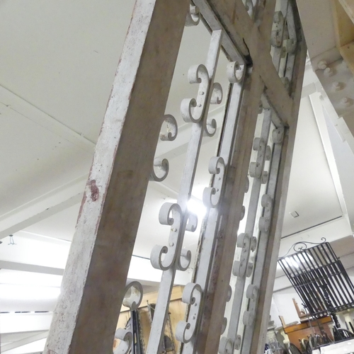 188 - A large panelled arch top door, with opening glass panes and wrought iron decoration. 90x245cm.