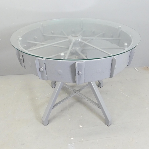 205 - A contemporary circular glass topped table, on painted tractor wheel base. 95x76cm