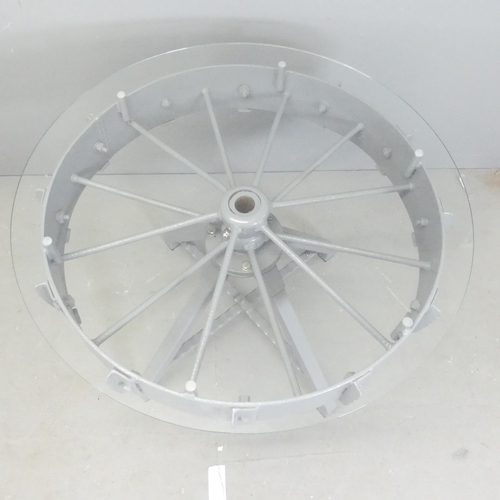 205 - A contemporary circular glass topped table, on painted tractor wheel base. 95x76cm