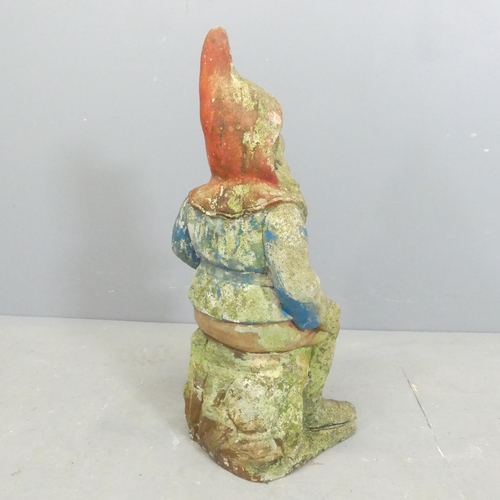 209 - A painted and weathered stone gnome garden ornament. Height 65cm.