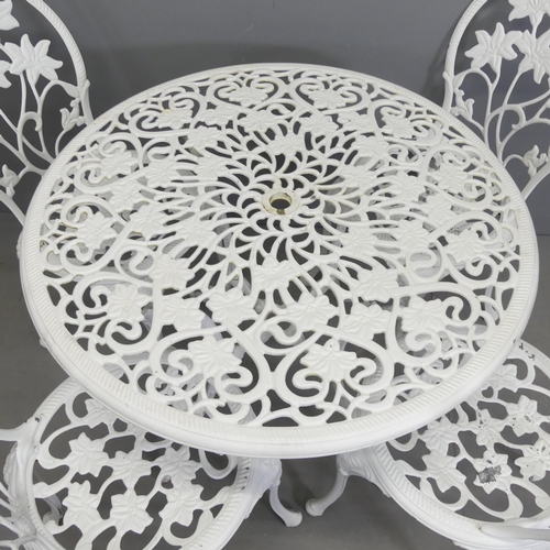 260 - A painted aluminium circular topped garden table with foliate design, 85x69cm, and four matching cha... 