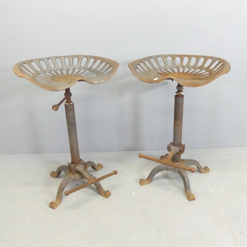 264 - A pair of cast iron tractor seat bar stools with height adjustable seats and footrests.