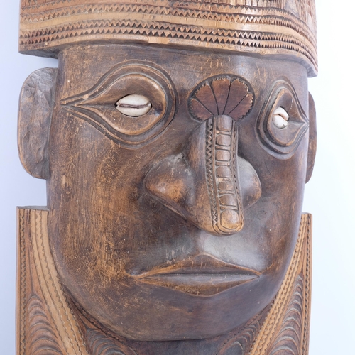 212 - A large South Seas hardwood wall plaque sculpture, with chip carved decoration and cowrie shell eyes... 