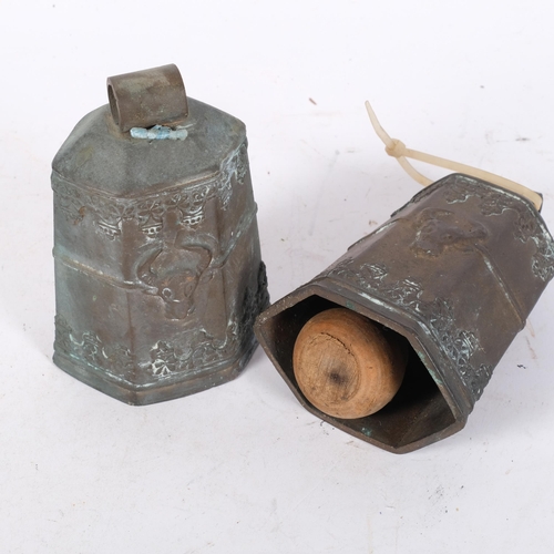 1042 - A pair of hexagonal embossed bronze cowbells, with cow's head and building decoration, and wooden cl... 