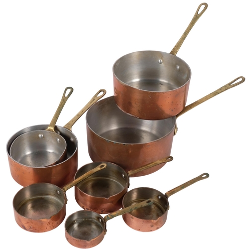 855 - A graduated set of copper pans with brass handles