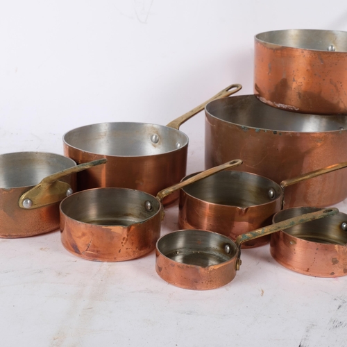 855 - A graduated set of copper pans with brass handles