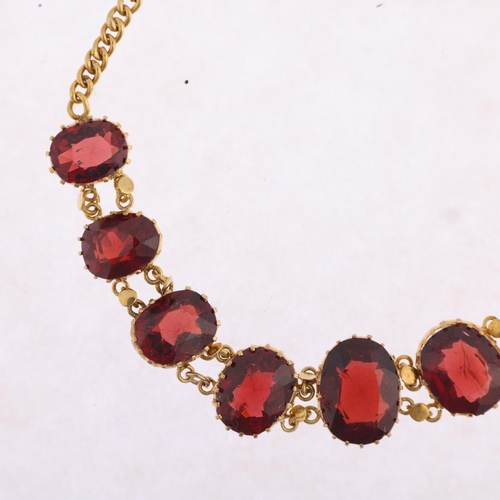 1161 - An Edwardian graduated garnet line bracelet, claw set with oval mixed-cut garnets, on curb link chai... 