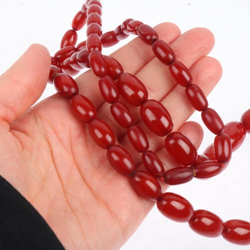 1526 - A long single-strand graduated cherry amber bead necklace, beads measure: 28.3-12.9mm, 46cm, 69.9g