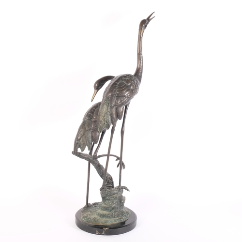 1 - A pair of verdigris bronze cranes on naturalistic base and metal stand, H75cm, base width 20cm