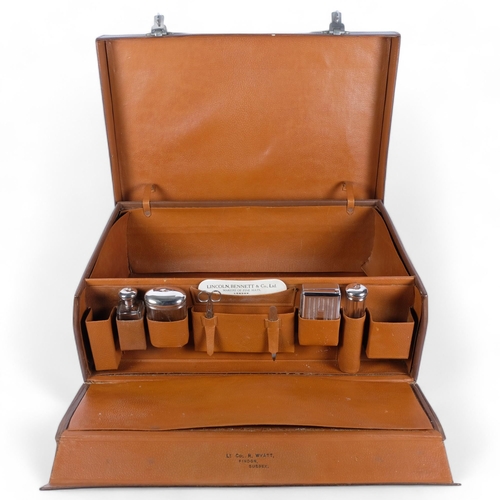 84 - An early 20th century leather-covered gentleman's travelling vanity suitcase, the lid opening to rev... 