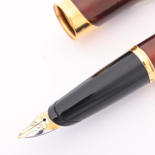 506 - A Parker Ellipse fountain pen, 18k gold nib, red lacquer body with gold plated mounts, in presentati... 