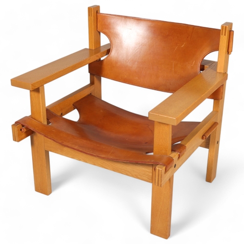 GUNNAR GUDMUNDSSON, a mid-century “Chief” safari style lounge chair in oak with saddle leather sling seat and back, made by Kristiani Siggierson of Reykjavik, Iceland, 1960, height 71cm , width 69cm, depth 69cm