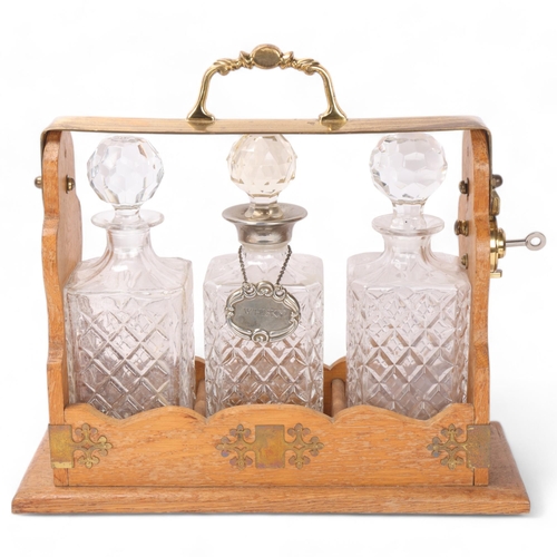 886 - A brass-mounted oak 3-bottle tantalus, with moulded glass decanters, length 39cm