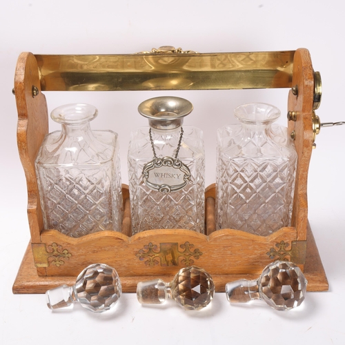 886 - A brass-mounted oak 3-bottle tantalus, with moulded glass decanters, length 39cm