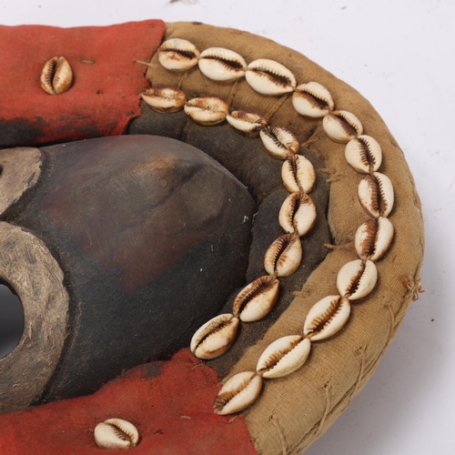 766 - A Dan hardwood Tribal mask in cowrie shell and textile surround, height 31cm