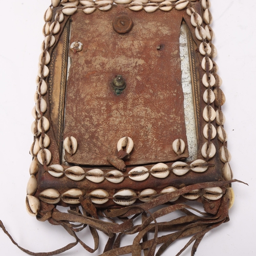 772 - An African Tribal chest plate, with inset mirror decorated with cowrie shells, approx 25cm x 19cm