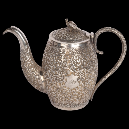 2765 - An Indian Kutch silver teapot, circa 1920, allover relief embossed floral decoration with bird knop,... 