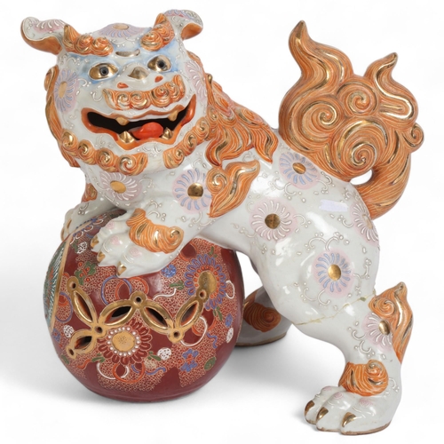 253 - A modern Kutani ceramic dog of fo, dog has raised front legs resting on ball, H26cm