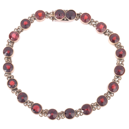 1118 - An Austro-Hungarian 14ct gold? garnet tennis line bracelet, circa 1900, millegrain set with round fa... 