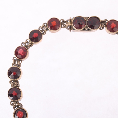 1118 - An Austro-Hungarian 14ct gold? garnet tennis line bracelet, circa 1900, millegrain set with round fa... 