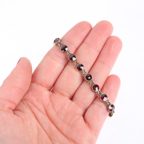 1118 - An Austro-Hungarian 14ct gold? garnet tennis line bracelet, circa 1900, millegrain set with round fa... 