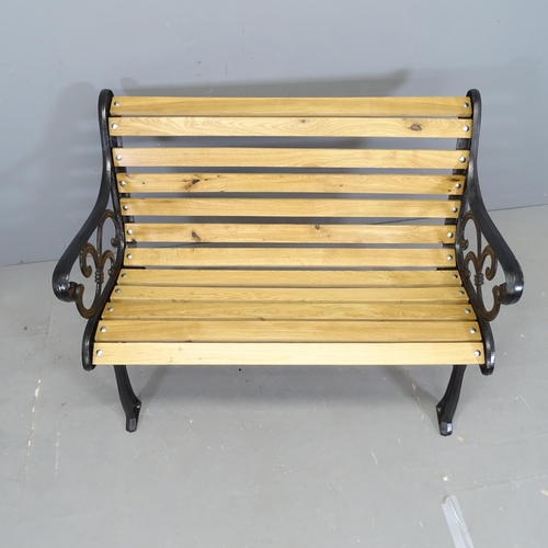 3028 - An oak slatted garden bench, with painted cast iron ends. 107x87x65cm.