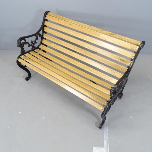 3029 - An oak slatted garden bench, with painted cast iron ends. 128x76x64cm.