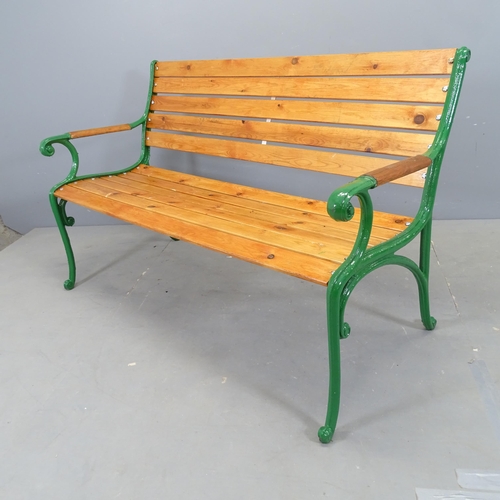 3031 - A stained pine slatted garden bench with painted cast iron ends. 136x82x64cm.