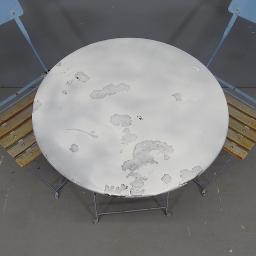 3039 - A circular painted metal folding bistro table, 60x71cm, and two Parisienne folding café chairs.