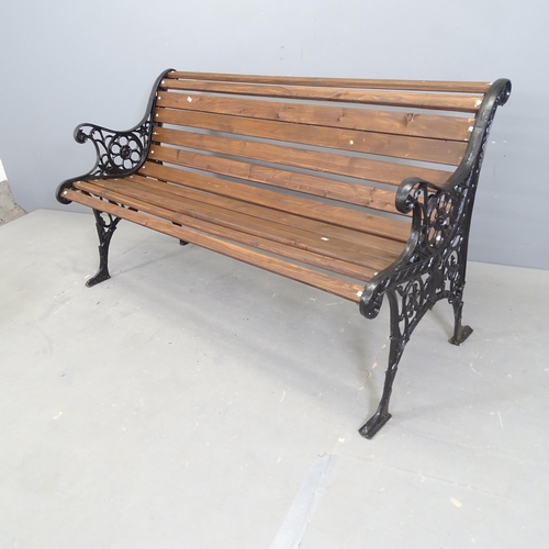 3071 - A stained pine slatted garden bench with painted cast iron ends. 132x72x60cm.