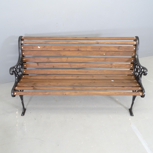 3071 - A stained pine slatted garden bench with painted cast iron ends. 132x72x60cm.