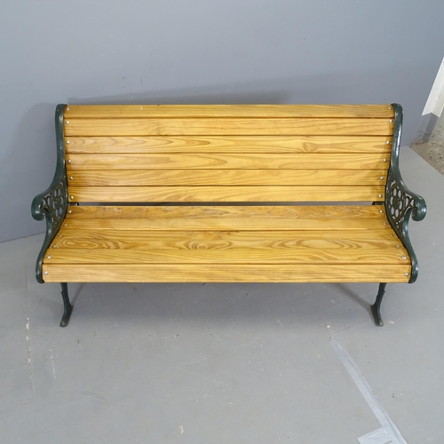 3077 - A stained pine slatted garden bench with painted cast iron ends. 142x75x65cm.