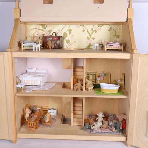 942 - A modern wooden doll's house with 3 floors, containing various furniture and Sylvanian Families figu... 